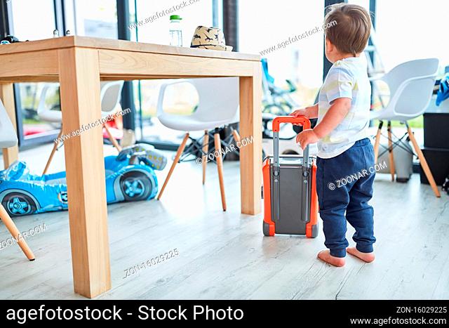 Kleinkind spielt Verreisen mit einem Koffer im Wohnzimmer