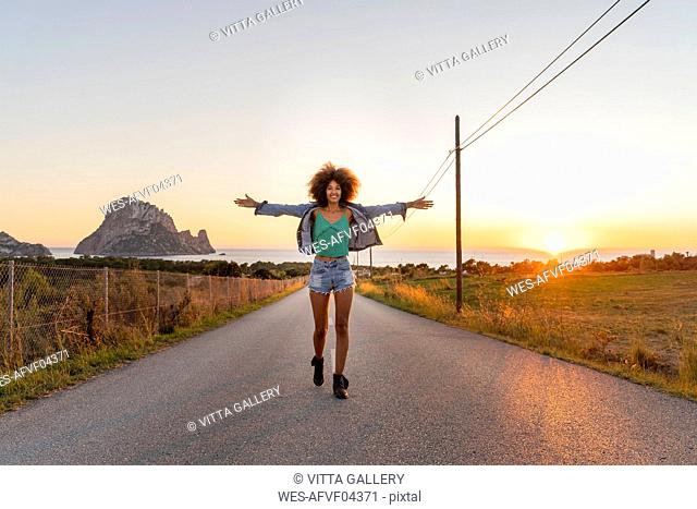 Young woman standing on street at sunset, Ibiza