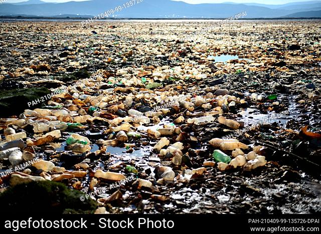 07 April 2021, Bolivia, Oruro: Orange colored plastic bottles and garbage lie on Lake Uru Uru. According to the environmental agency of the government of Oruro