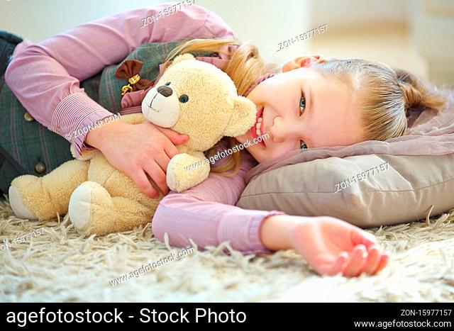 Mädchen kuschelt mit einem Teddybär im Arm