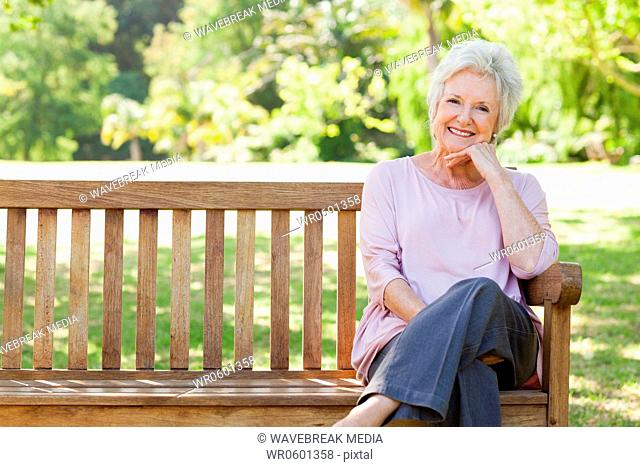 Woman smiling happily as she sits on a bench