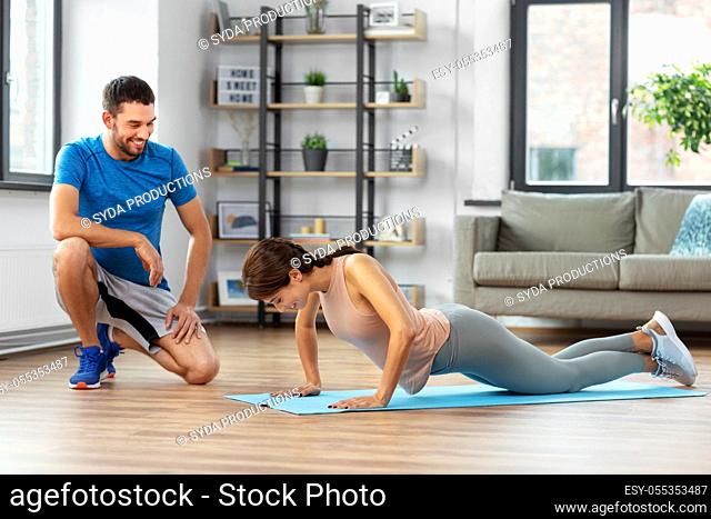 woman with personal trainer doing push-ups at home
