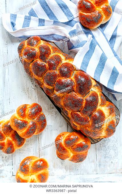 Challah bread with poppy seeds on a wooden table with a linen towel