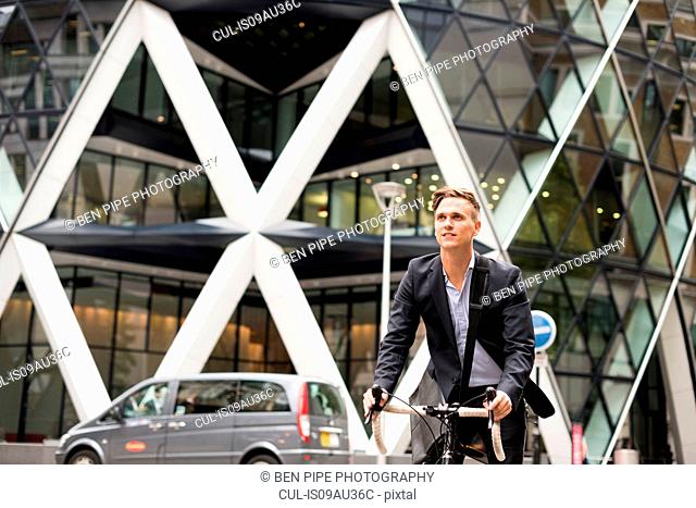 Businessman on bike, 30 St Mary Axe in background, London, UK