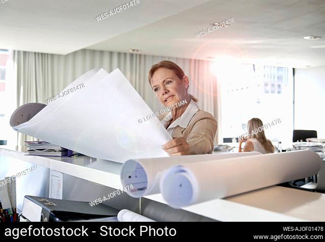 Businesswoman looking at blueprints in office