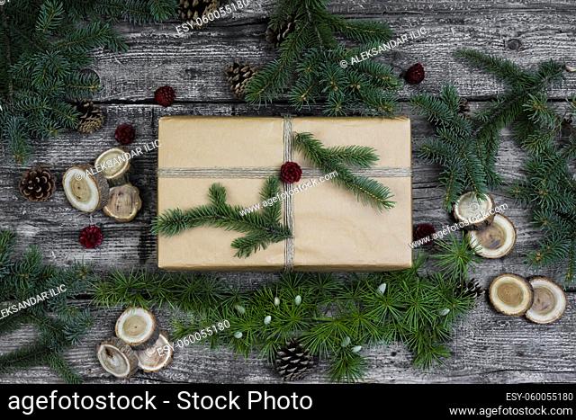 Gift box, present and decoration . Christmas tree branches and pine cones wooden background. Flat lay, top view