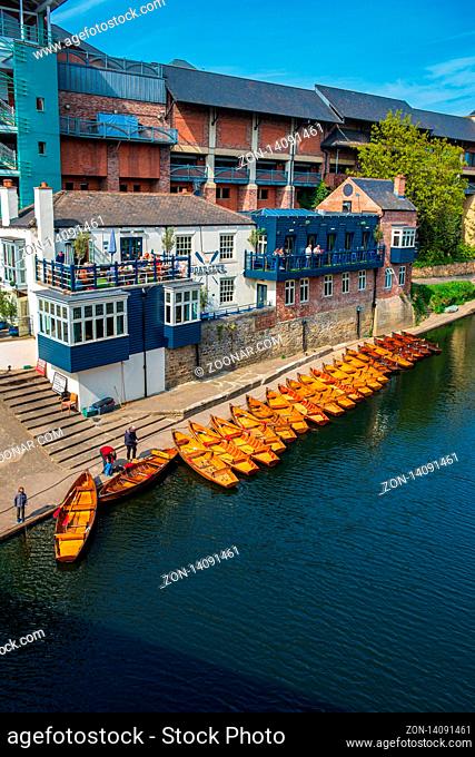 Durham, United Kingdom - April 30, 2019: Line of moored rowing boats on the banks of River Wear near a boat club in Durham