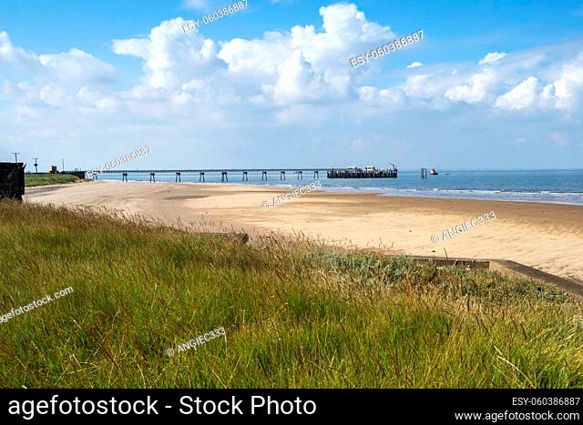 Grass, sandy beach and pilot boat jetty at Spurn Point, East Yorkshire, England, with a lovely blue sky