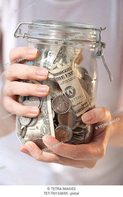 Close-up of woman holding jar of money