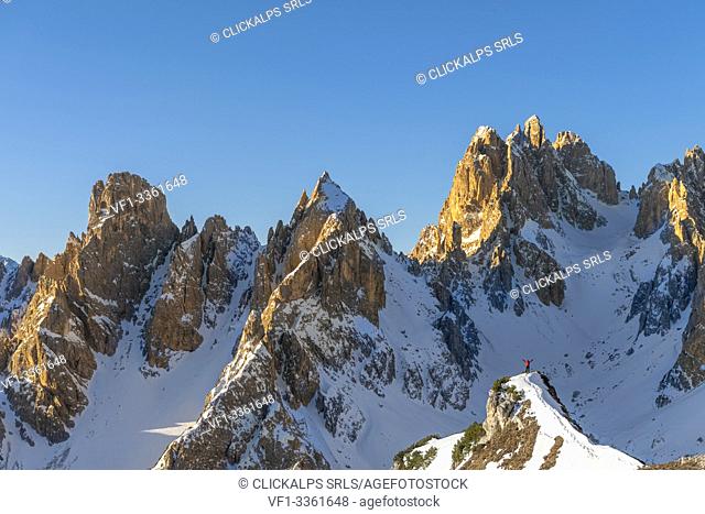 Mount Campedelle, Misurina, Auronzo di Cadore, province of Belluno, Veneto, Italy, Europe. A mountaineer admires the sunrise in the Cadini di Misurina mountains