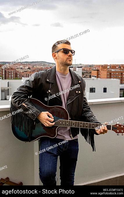 Young musician standing with guitar at rooftop
