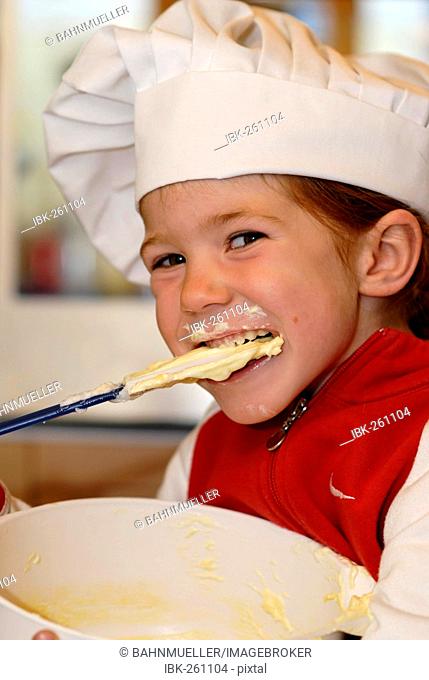 Girl enjoys and nibbles licks dough while baking