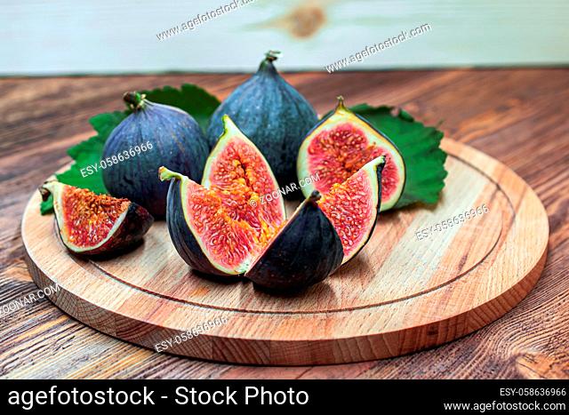 A few vivid cuted figs on a plate on an old wooden background