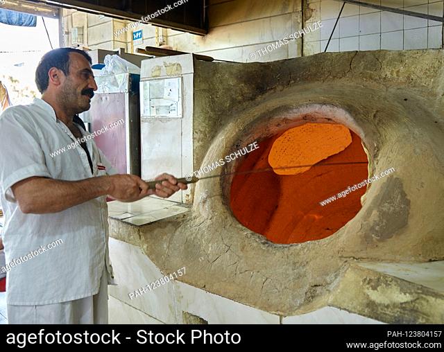 City view of the Iranian capital Tehran, a bread maker in his bakery with oven, taken on April 19, 2017. As an industrial and commercial city with universities