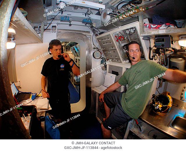 NEEMO 14 crew member Andrew Abercromby (left) and habitat technician Nate Bender perform communication checks with Mission Control from inside their undersea...