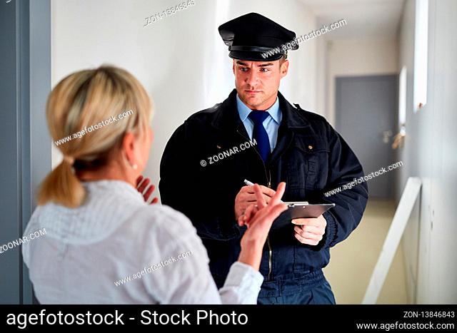 Polizist redet mit Frau bei Zeugenbefragung an der Wohnungstür nach einem Einbruch