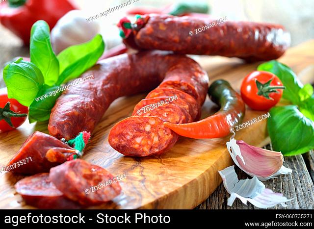 Spanische Spezialität: Luftgetrocknete scharfe Chorizo Paprikasalami auf Olivenholzbrett serviert ? Spanish salami: Spicy chorizo sausage with tomatoes and...