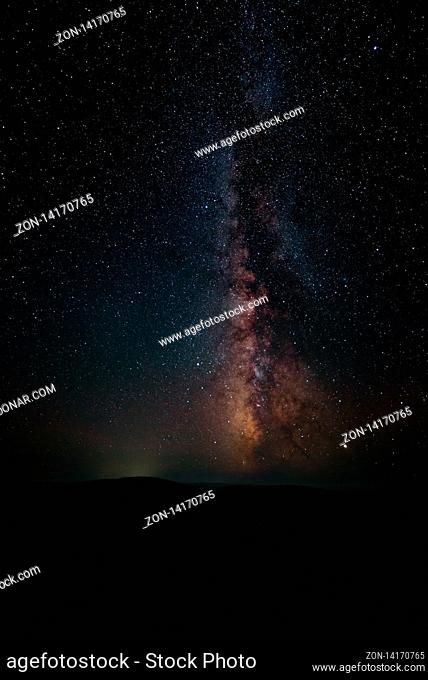 Milky Way and pink light at mountains. Night colorful landscape. Starry sky with hills at summer. Beautiful Universe. Space background with galaxy