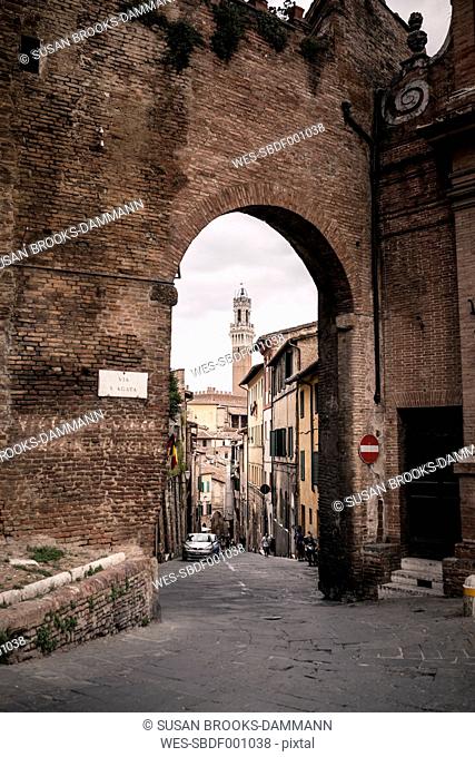 Italy, Tuscany, Siena, city gate with tower of Palazzo Pubblico in the background