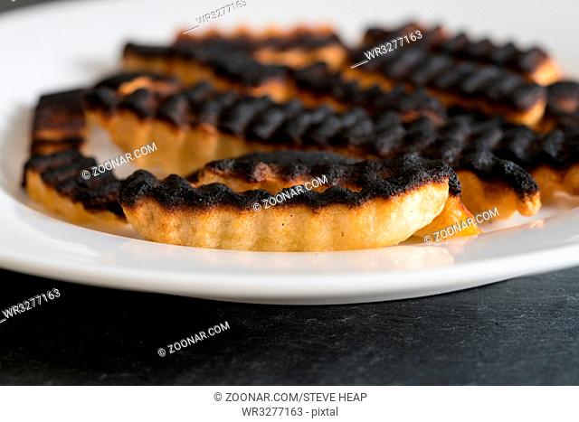 Burnt and ruined french fries or chips after leaving under the grill for too long and charring them