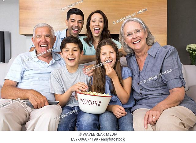 Portrait of happy extended family watching tv in living room