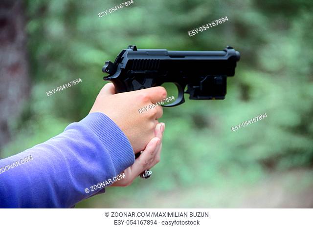 Woman shoots from airgun pistol (black air gun) in forest. Hands and arms visible, different camera angles