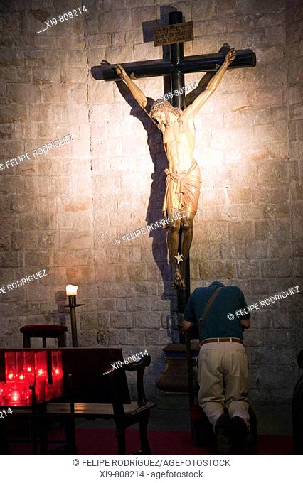 Man praying at the foot of a crucifix in the church of Santa Maria del Mar, Barcelona. Catalonia, Spain