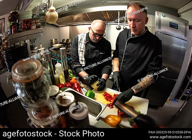 25 March 2020, Lower Saxony, Göttingen: The chefs Peter Goldmann (r) and Vincenzo Luigi Luggeri cut vegetables for a stew in the kitchen of the restaurant...