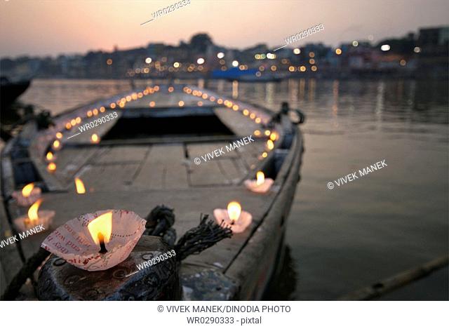 Lamps or diyas lighted on boat at banks of holy Ganga river , Varanasi , Uttar Pradesh , India