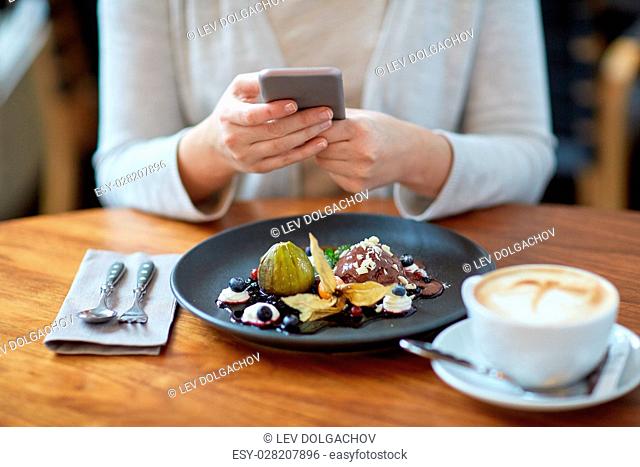 food, new nordic cuisine, technology, eating and people concept - woman with smartphone, chocolate ice cream dessert with blueberry kissel
