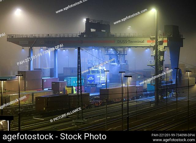 01 December 2022, Saxony, Leipzig: A truck semitrailer is reloaded with a crane early in the morning at the Leipzig-Wahren transshipment station