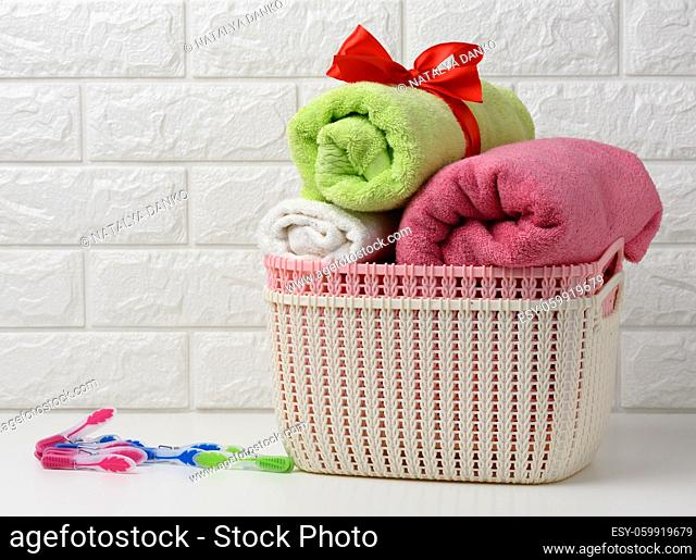 clean rolled terry towels in a plastic basket on a white shelf, bathroom interior