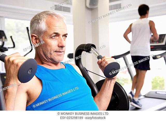 Man Using Weights Machine With Runner On Treadmill In Background
