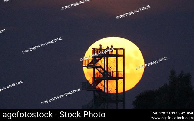 14 July 2022, Lower Saxony, Syke: Onlookers watch the moonrise from the observation tower on the Hohe Berg. The so-called supermoon is a celestial event that...