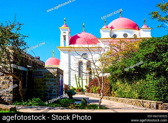 Israel. Orthodox monastery and church of the Twelve Apostles. Snow-white church with pink domes and golden crosses. Gorgeous green south park