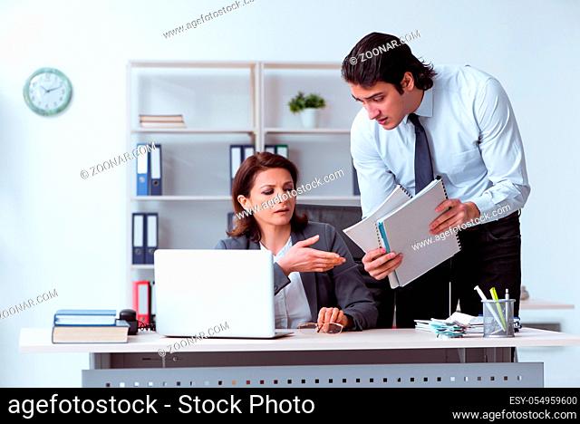 Old female boss and young male employee in the office