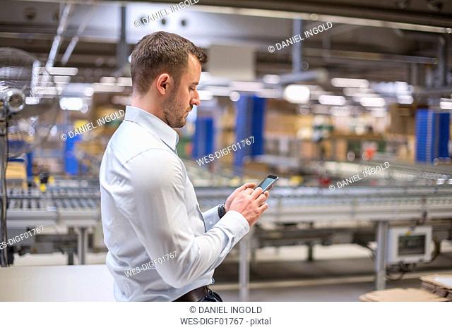 Man in factory looking at cell phone