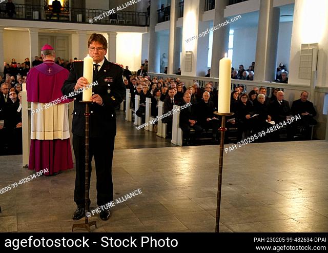 05 February 2023, Schleswig-Holstein, Neumünster: Uwe Schröder, Sarlhusen Volunteer Fire Department places a candle at the funeral service for the victims of...