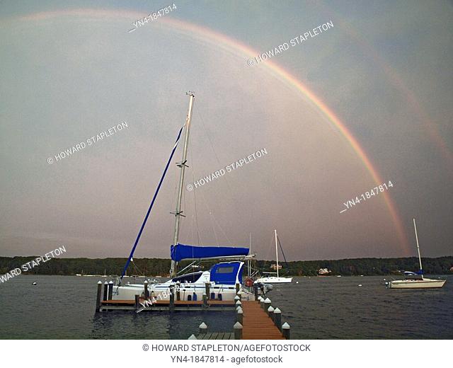 A double rainbow appears over Martha, s Vinyard, Massachusetts on a stormy day  Boats are moored in Laguna Pond, an Atlantic Ocean inlet