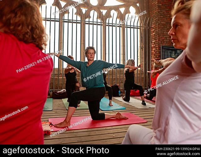21 June 2023, Saxony-Anhalt, Halberstadt: Participants in a yoga session begin their exercises on the towers of the Martini Church in Halberstadt