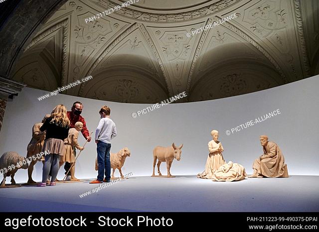 23 December 2021, Berlin: Edgar (9) and Maya (8) help their father Andreas Lobeda, house craftsman of the Berlin Cathedral, to assemble the nativity scene