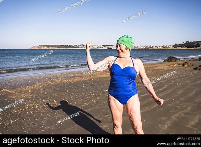 Woman showing biceps at beach on sunny day