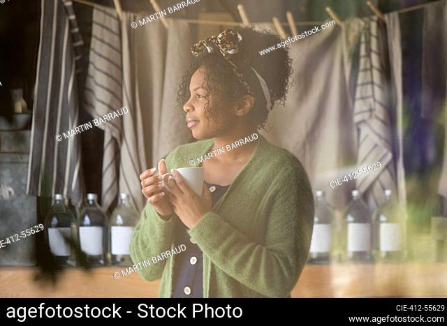 Thoughtful female shop owner drinking coffee