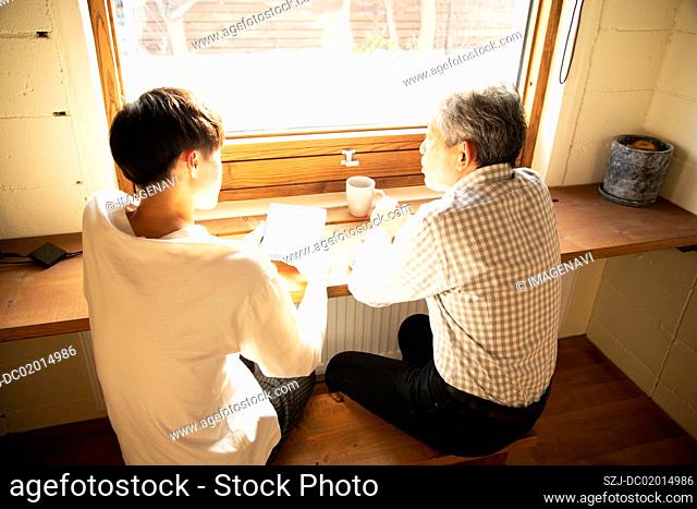 Senior and young people talking with smile by window