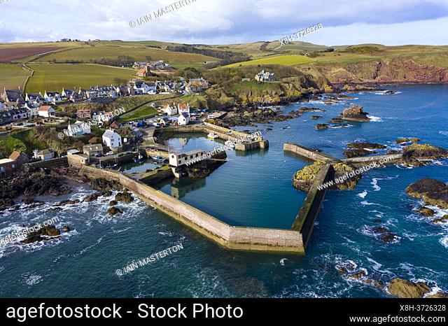 Aerial view of small fishing village and harbour of St Abbs on North Sea coast in Scottish Borders, Scotland, UK