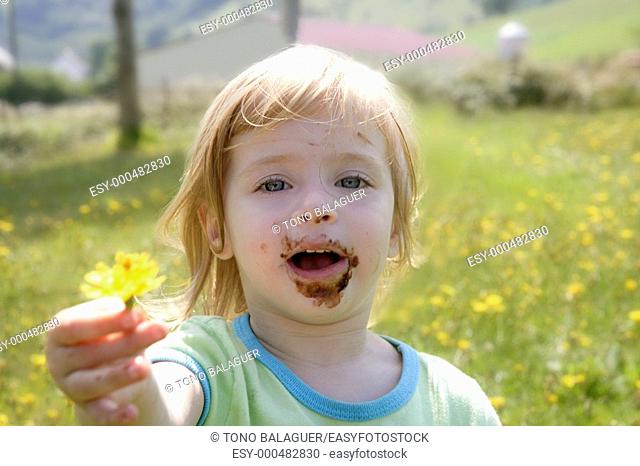 Adorable little girl eating chocolate outdoor field