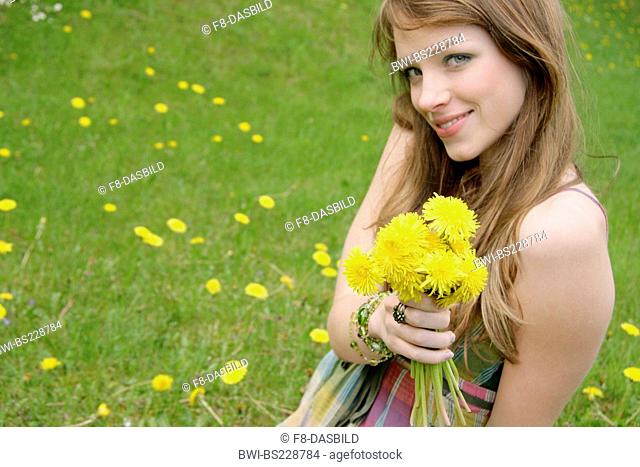 young woman in a meadow with flowers in her hand