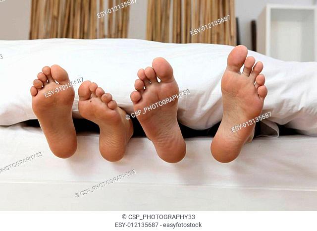 male and female feet in bed
