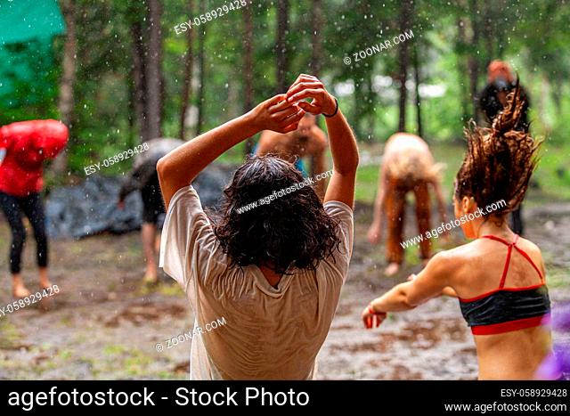 A large group of men and women experience mindful dance and meditation in a muddy woodland clearing during a nature retreat