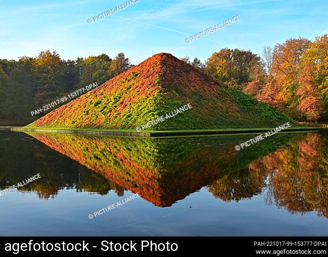 17 October 2022, Brandenburg, Cottbus: The morning sun shines on the autumnal lake pyramid in Prince Pückler Park in Branitz
